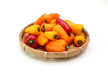 白背景の様々な色の笊にいれたカラーピーマン