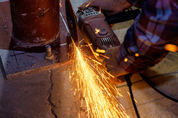 While grinding iron worker uses an abrasive disk to cut metal with spark