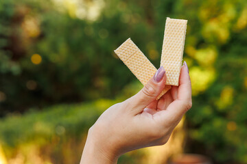 Woman's hand holds waffles, snack and fast food concept. Selective focus on hands with blurred...