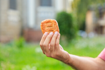 A guy's hand holds a mini puff pastry with cheese, snack and fast food concept. Selective focus on...