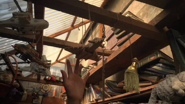 a female hand with a neat manicure and a green ring carefully touches a toy airplane hanging on a wooden beam under a glass ceiling in an old book market.