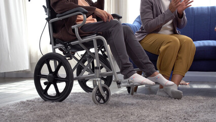 Wheelchair with legs paralysis patient elderly woman sitting talk friend in living room at home. Paralyzed grandmother problem legs sitting on wheelchair conversation friend visit support at room. - obrazy, fototapety, plakaty