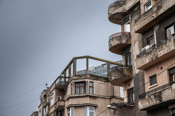 Selective blur on residential buildings, flats and apartments in a small street of Bucharest city center, with a typical southeastern european chaotic urbanism, decaying in bad condition, ruined.