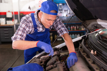 Positive man car mechanician repairing car in auto repair shop