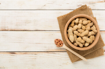 Unpeeled peanuts on wooden background, top view