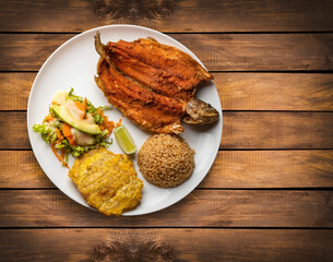 Fried trout accompanied with patacon, coconut rice and vegetable salad - Colombian food