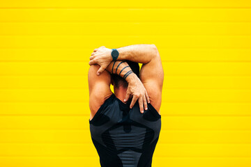 Muscular man stretching hands in city