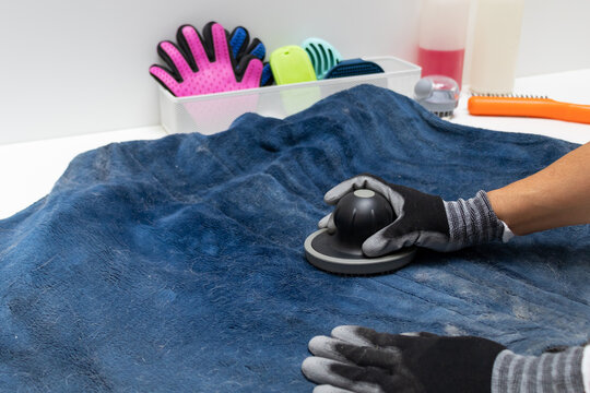 Cropped view of a person using a lint remover on a blue pet blanket