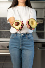 Woman holds a green cut avocado in her hands. Avocado close-up. Healthy food, raw food diet. Vegetarian life. Proper nutrition. Eco product. Poster