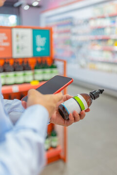 Man using cellphone and checking bottle label in store