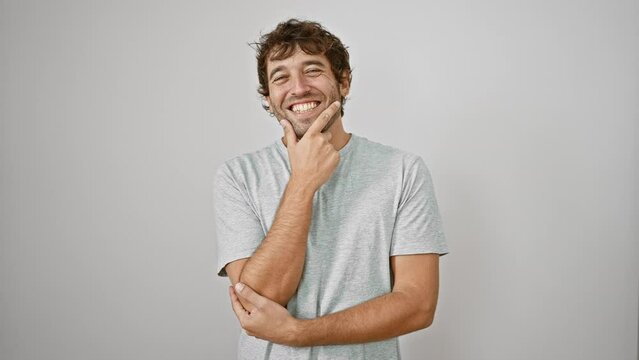 Young man wearing a t-shirt looking confident at the camera smiling with crossed arms and hand raised on chin. thinking positive. over isolated white background