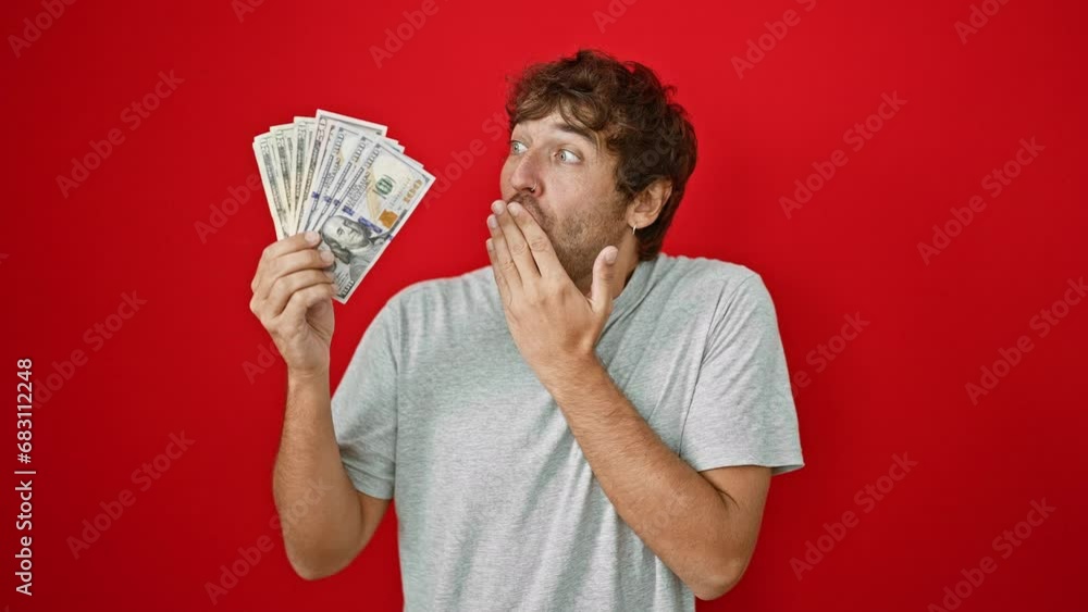 Poster Young blond bearded guy, shocked and quiet, covering mouth with hand, surprised by a secret regarding american us banknotes. fear and shame expressed over isolated red background.