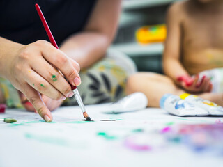 Naklejka premium Children and mother painting images with water color on the paper and making prints by hands and foots.