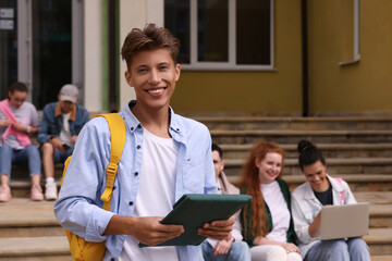 Students learning together on steps. Happy young man with tablet outdoors, selective focus - Powered by Adobe