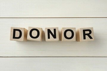 Word Donor made of cubes on white wooden table, top view