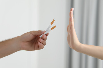 Stop smoking concept. Woman refusing cigarettes on blurred background, closeup