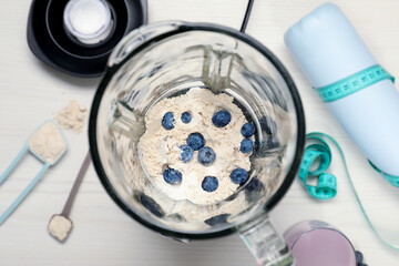 Making shake. Blueberries and powder in blender on white table, top view