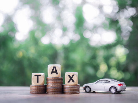 Toy car and wooden blocks with the word TAX on stack of coins. The concept of saving and mamage money to success transportation, Paying tax and car loan