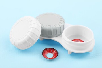 Case with red contact lenses on light blue background