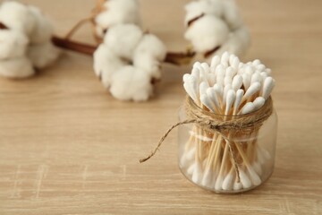 Fototapeta na wymiar Cotton swabs and flowers on wooden table, closeup. Space for text