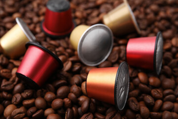 Many different coffee capsules on beans, closeup