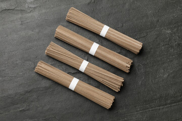 Uncooked buckwheat noodles (soba) on black table, top view