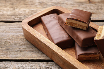 Tasty chocolate bars with nougat on wooden table, closeup