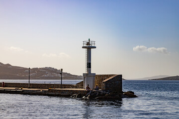 Fototapeta premium People sitting near the lighthouse in Mykonos, Greece