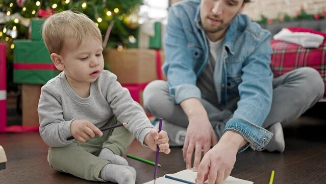 Father and son celebrating christmas drawing on notebook at home