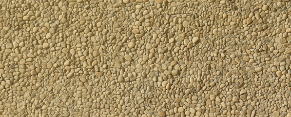 Texture of a stone wall with small round pebble stones. Part of a stone wall as a background or texture in the sunlight