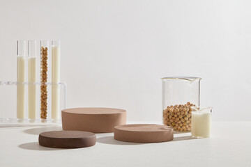 Podiums in brown color decorated with few beakers and test tubes filled with soybean milk and soybean seeds. Minimal podium display for cosmetic product presentation