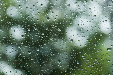 Raindrops adorn windowpane, creating a melancholic ambiance, symbolizing solitude, introspection, and nature's serene beauty on a rainy day