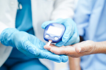 Asian doctor using digital glucose meter for check sample blood sugar level to treatment diabetes.