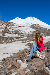 Girl sitting on the rock overlooking Elbrus mountain, Russia