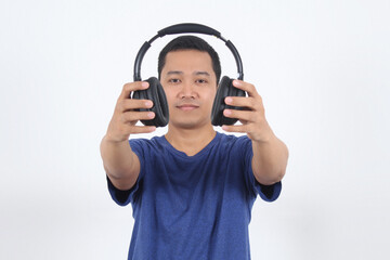 Smiling Asian man in casual blue navy t-shirt  giving and showing black earphone to camera