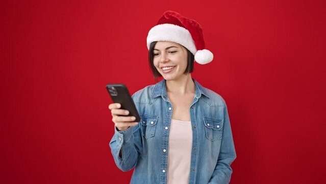 Young caucasian woman taking a selfie picture wearing christmas hat over isolated red background