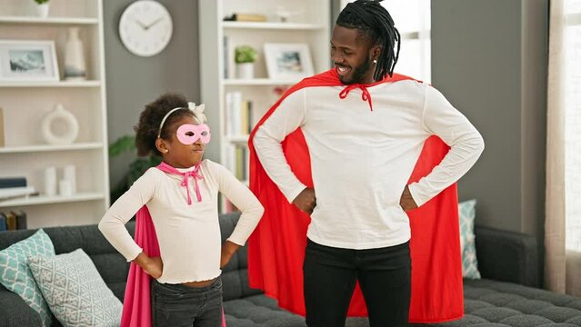 African american father and daughter smiling confident wearing superhero costume standing at home