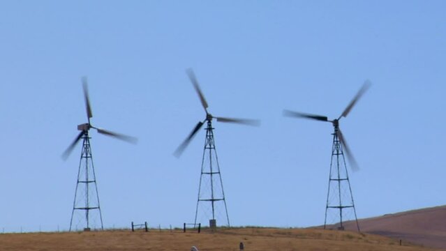 Wind turbines working in Altamont Pass wind farm against blue sky on a sunny day in California, USA