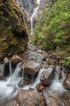 Fast flowing, rocky, mountain stream with the Waitonga Falls in the background. On the flanks of Mount Ruapehu, Tongariro National Park, New Zealand.
