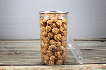 Pile of fresh and organic caramel popcorn in the plastic container. Mock up of snack product...