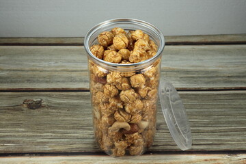 Pile of fresh and organic caramel popcorn in the plastic container. Mock up of snack product concept.