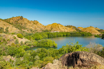 Fototapeta premium Where mountains meet the sea, Labuan Bajo unveils its coastal wonders. Majestic hills embrace the shoreline, creating a breathtaking panorama that captures the essence of nature's harmony.