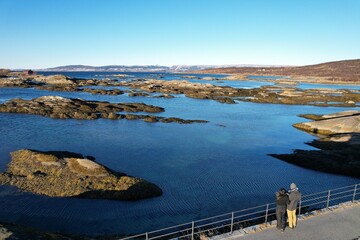 A couple stands by the quiet, rocky shores of Norway's coastline