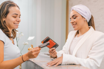 Woman paying on the reception desk in beauty treatment clinic - obrazy, fototapety, plakaty