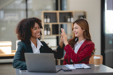 Two young businesswoman smiling happy giving high five at the office. Two business woman who...