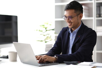 Businessman working with laptop on desk in office.