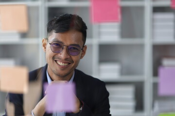 Businessman thinking and planning work with sticker on glass plate in office.