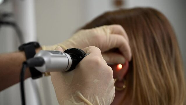 otolaryngologist conducts medical examination of ear with otoscope closeup