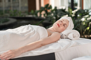 Obraz na płótnie Canvas Relaxed young woman lying on massage table with closed eyes in spa resort.