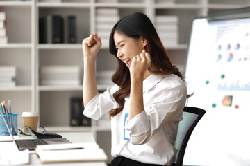 A woman using laptop looks excited, happy to succeed and receive a bonus.